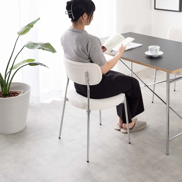 ホワイトのもこもこな素材のダイニングチェアに腰掛けている様子