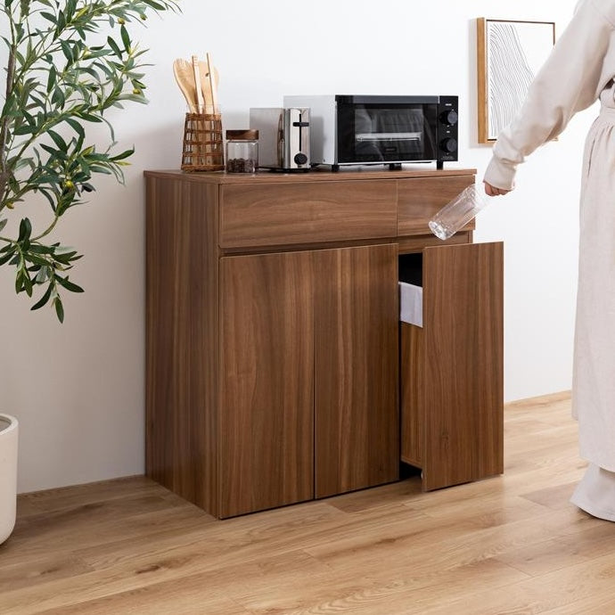 ブラウンカラーのゴミ箱とキッチンボードが一体となった収納家具を置いているキッチン