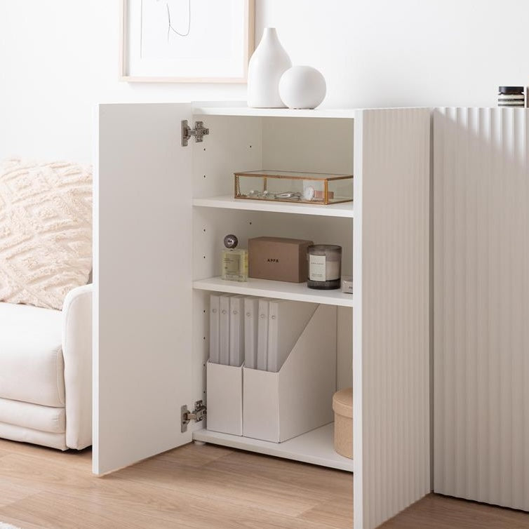 波型扉のホワイトのキャビネットにアクセサリーや書類、香水などが収納されている様子