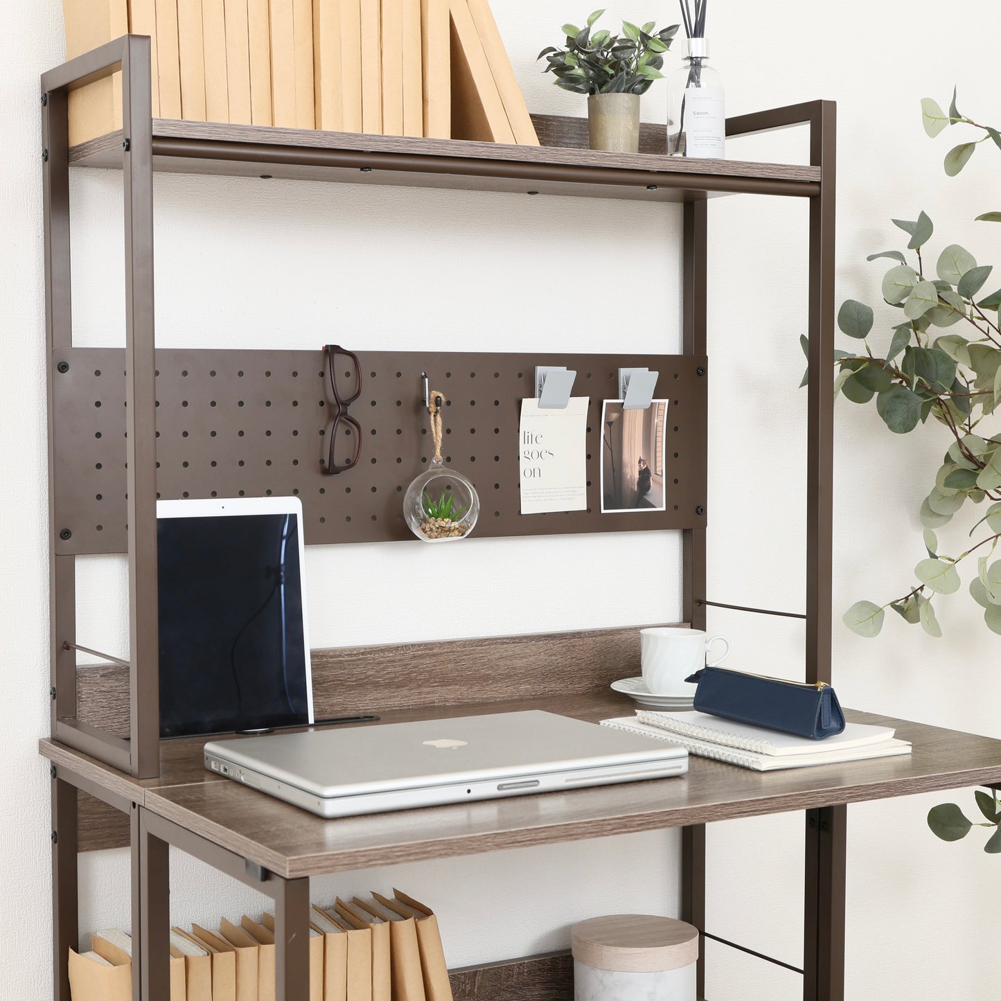 天板が折りたためる収納棚が付いたデスクにパソコンや本が置かれている様子