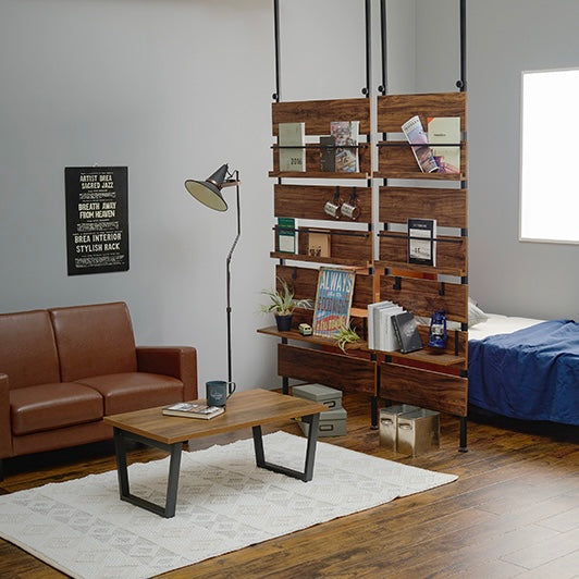 ブラウンの突っ張りディスプレイラックを部屋の仕切りとして2つ並べて設置している様子