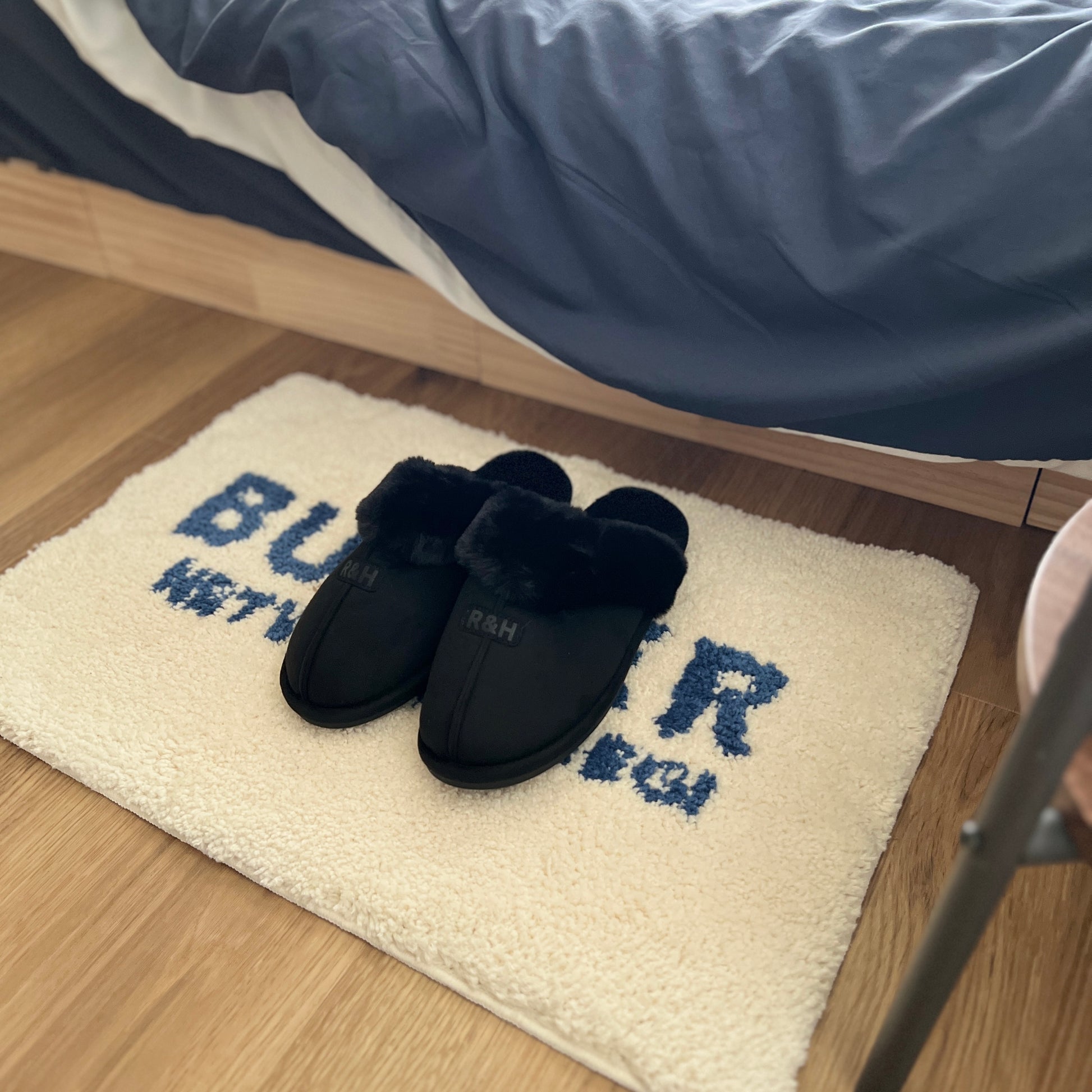 ブラックのムートン調のファースリッパをミニラグの上に置いている様子