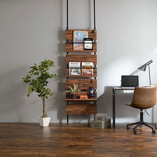 ブラウンの突っ張りディスプレイラックをデスク横に設置している様子