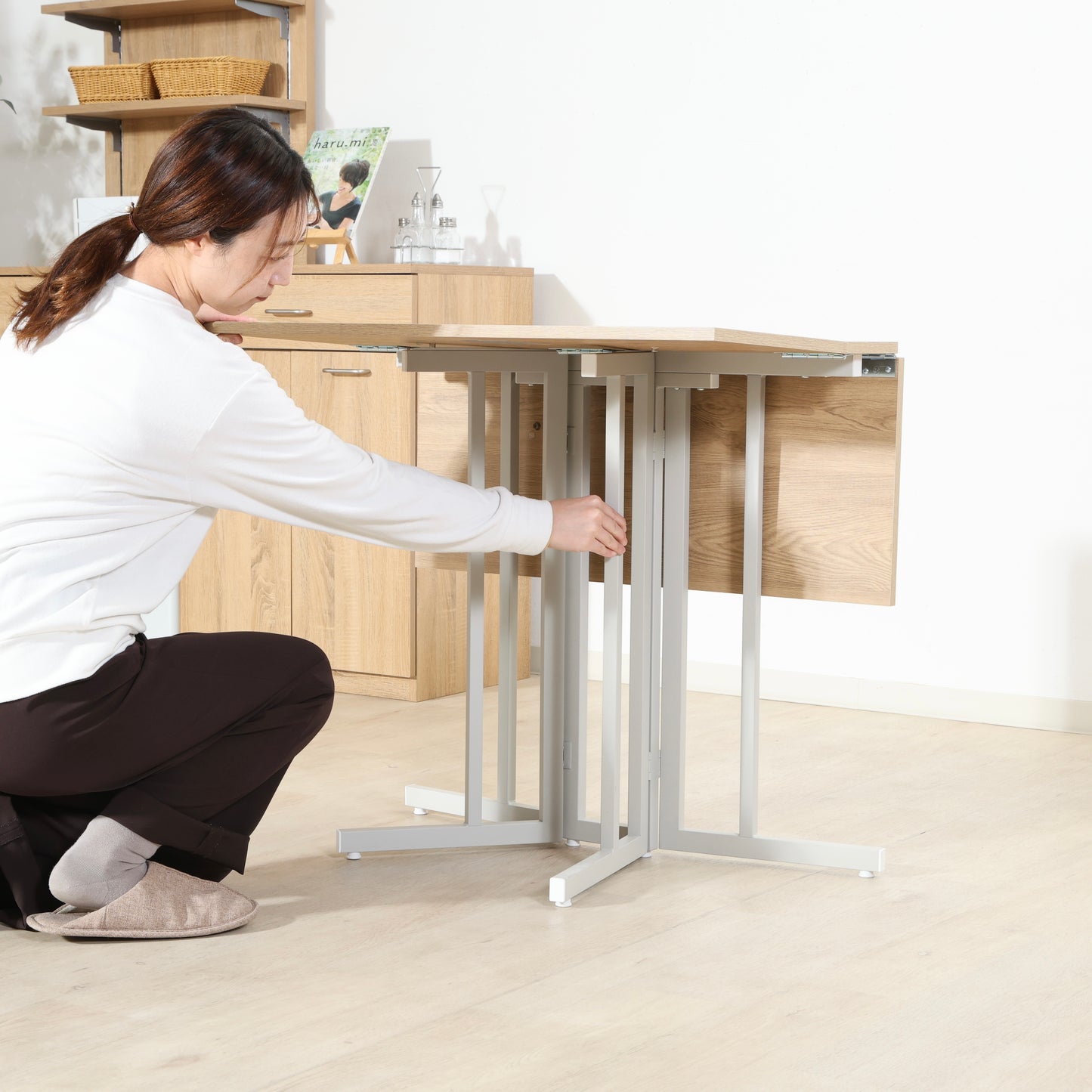 ウッド天板とスチール脚の異素材組み合わせの折りたたみ式のダイニングテーブルを折りたたんでいる様子