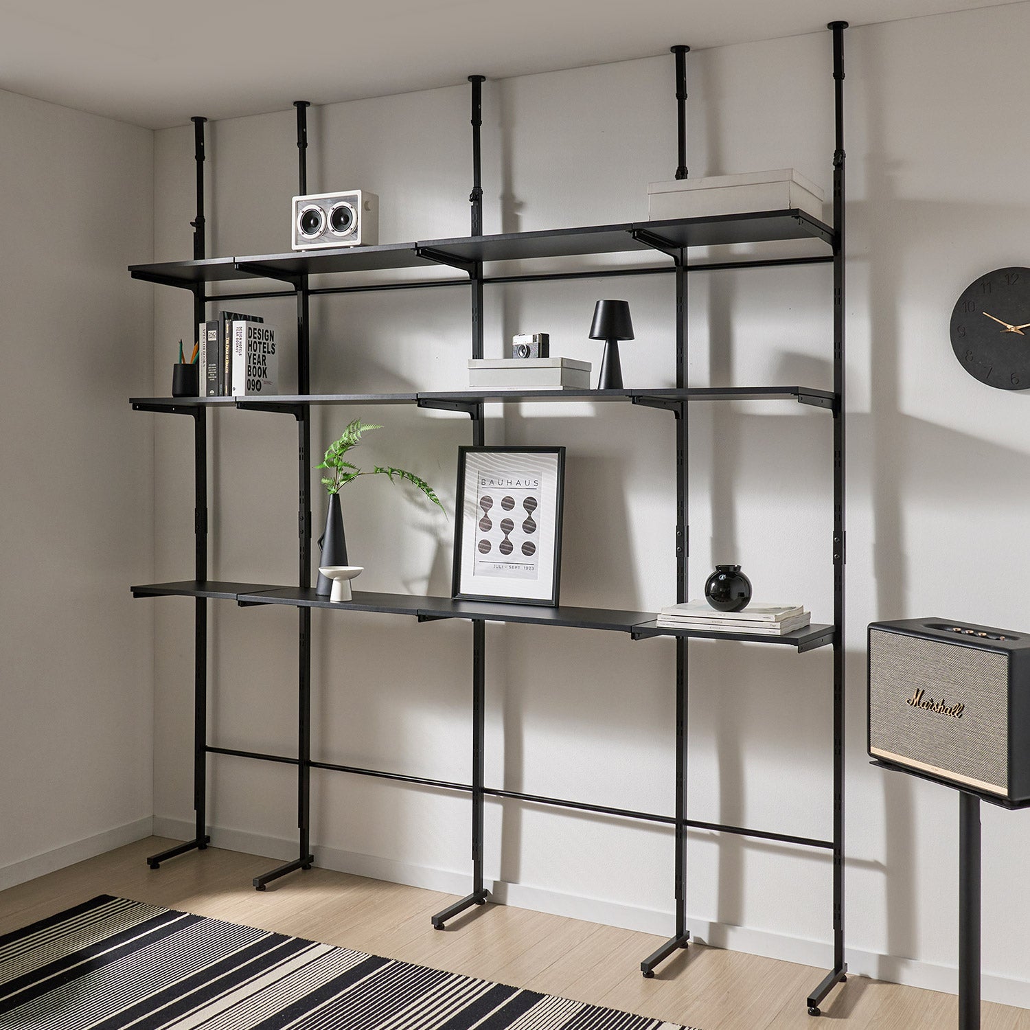 Roomnhomeのエルパ突っ張りカスタムシェルフは黒の金属製で調整可能な棚板を持つ工業デザインの収納棚です
