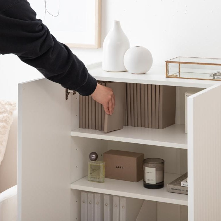 波型扉のホワイトのキャビネットの中に入ってある本を取ろうとしている様子