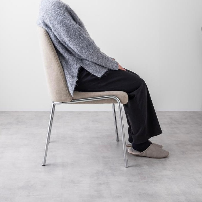 シルバー脚がお洒落なファブリック素材のチェアにひ人が座っている