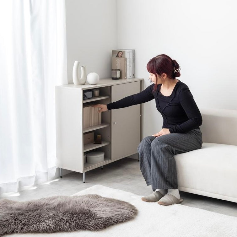 リビングに置かれた扉がスライド式の棚に人が手を伸ばしている