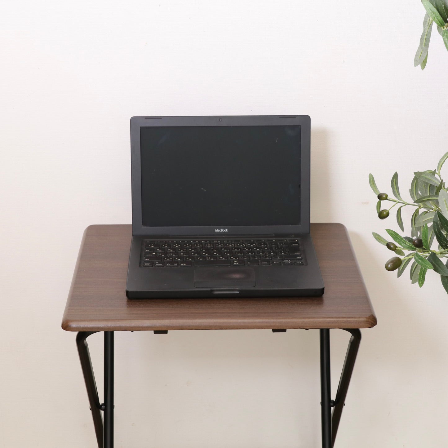 黒のmacbookが黒い金属脚の木目調折り畳みコンパクトテーブルに置かれている画像