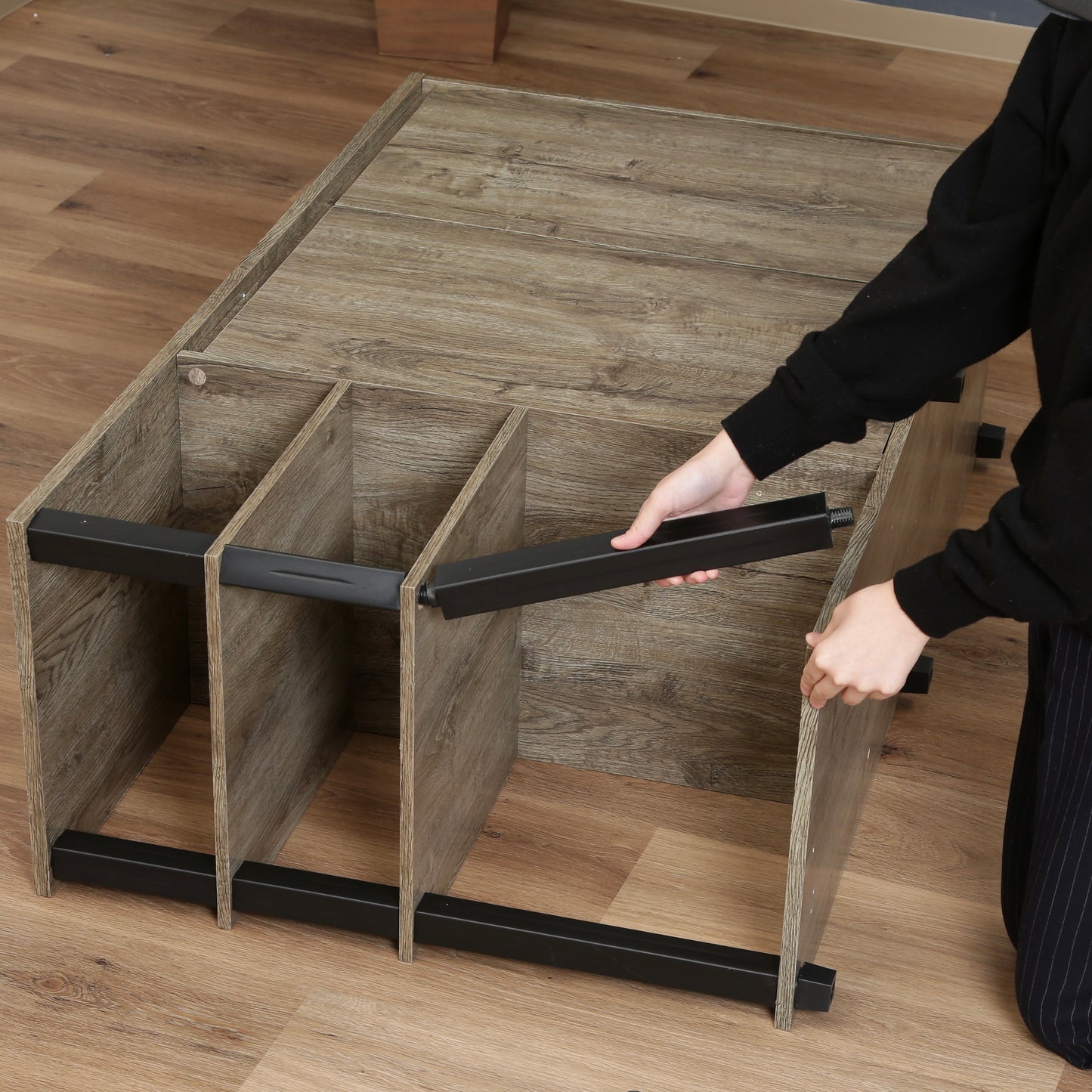 オープンラックが一体になった、ウッド素材のキャビネットを組み立てている様子