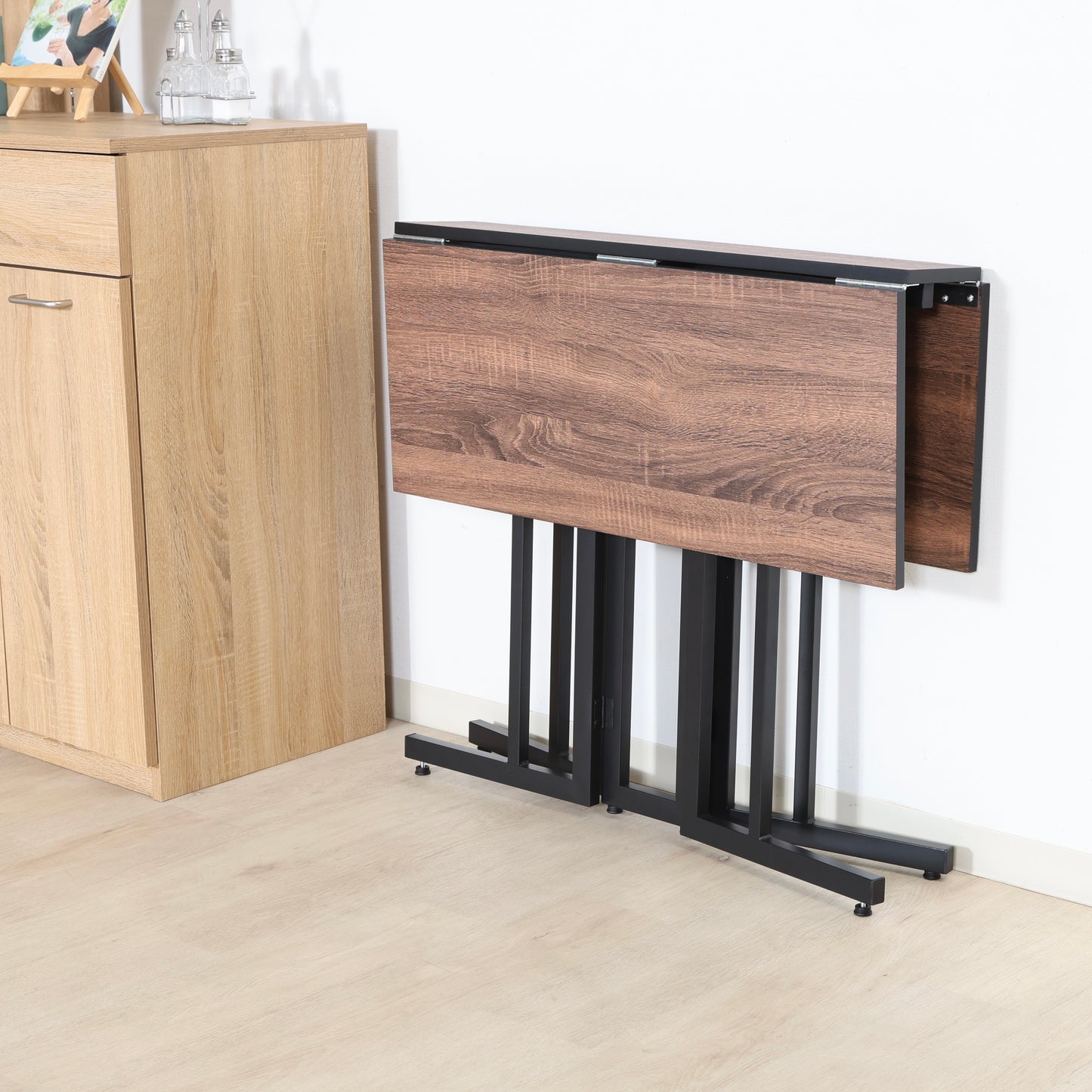 ウッド天板とスチール脚の異素材組み合わせの折りたたみ式のダイニングテーブルが折り畳まれている様子