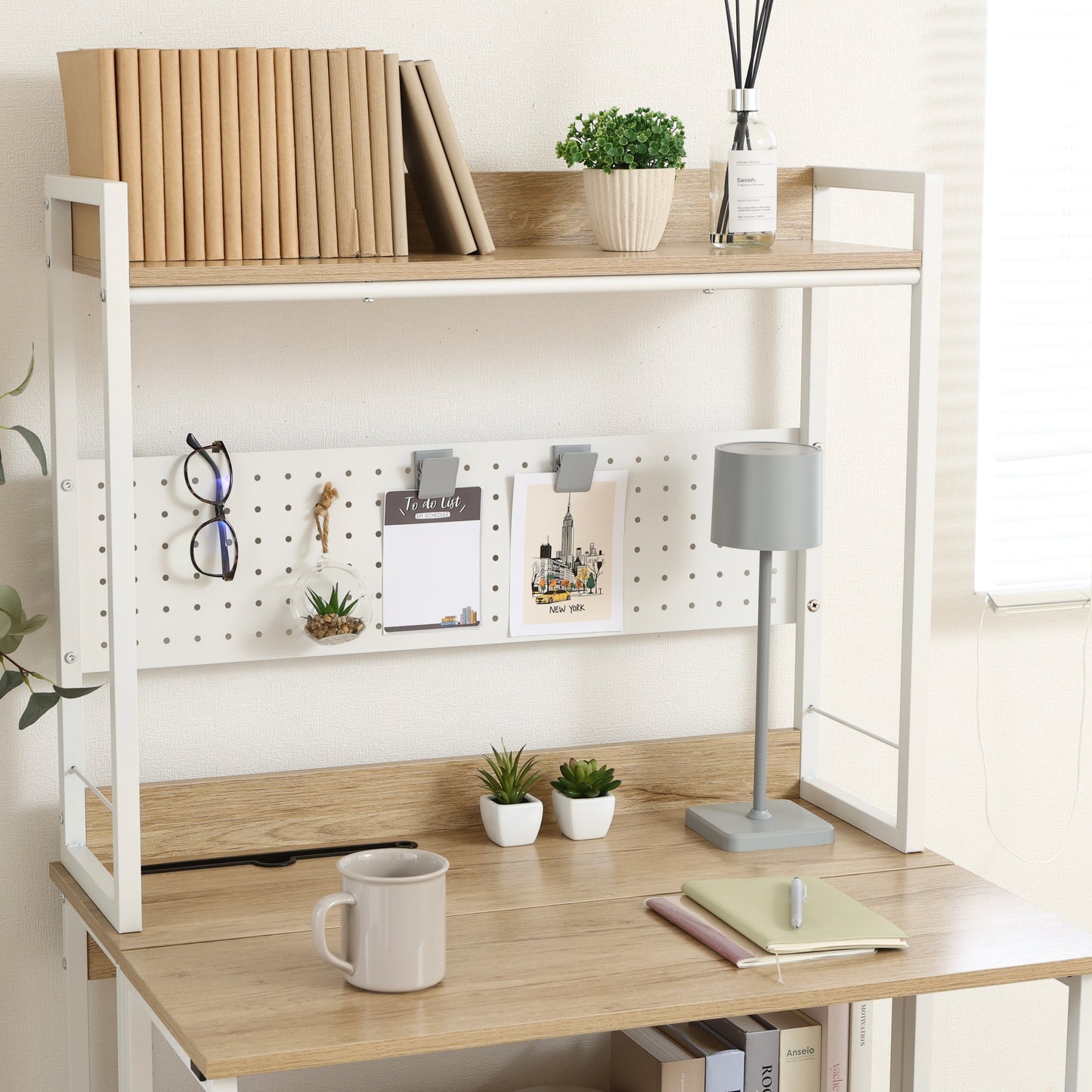 天板が折りたためる収納棚が付いたデスクに文房具や本が置かれている様子