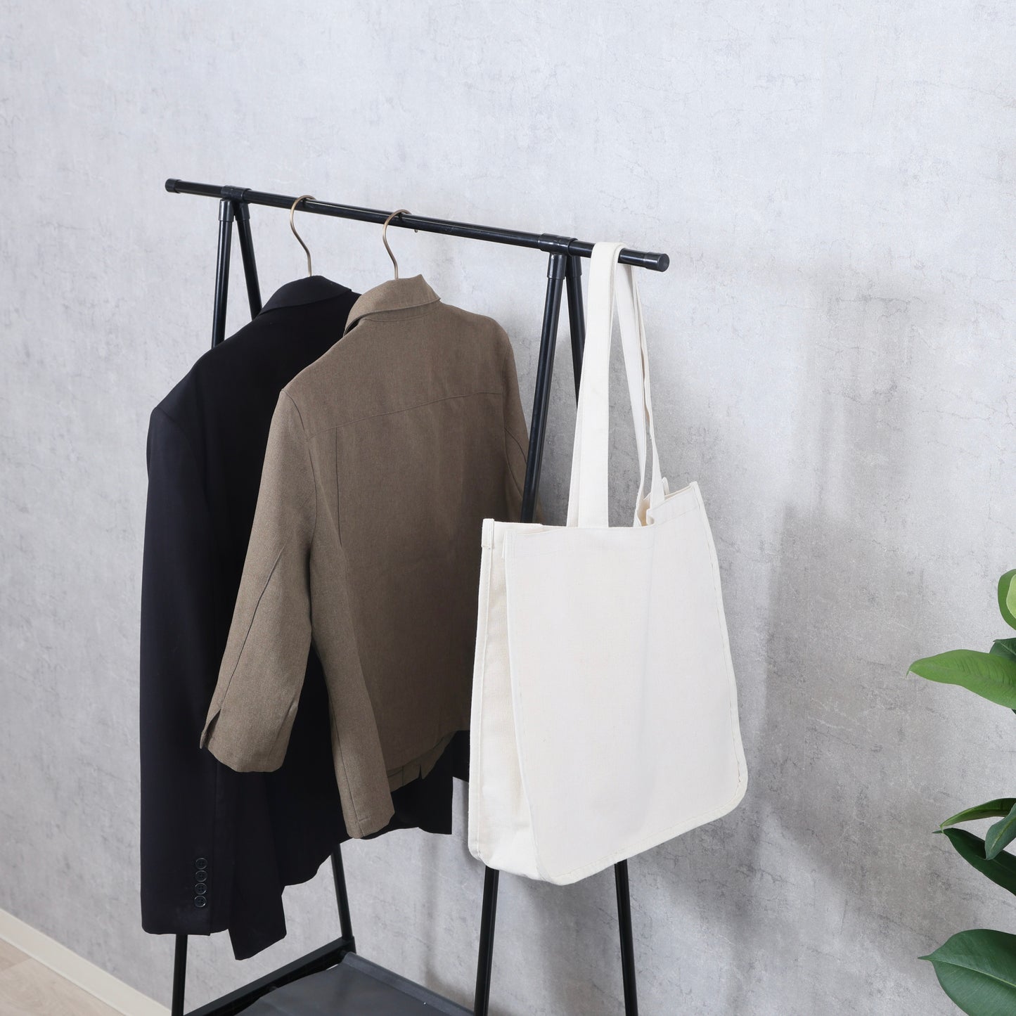 棚がついたオープンなハンガーラックに洋服やバッグが掛けられている様子