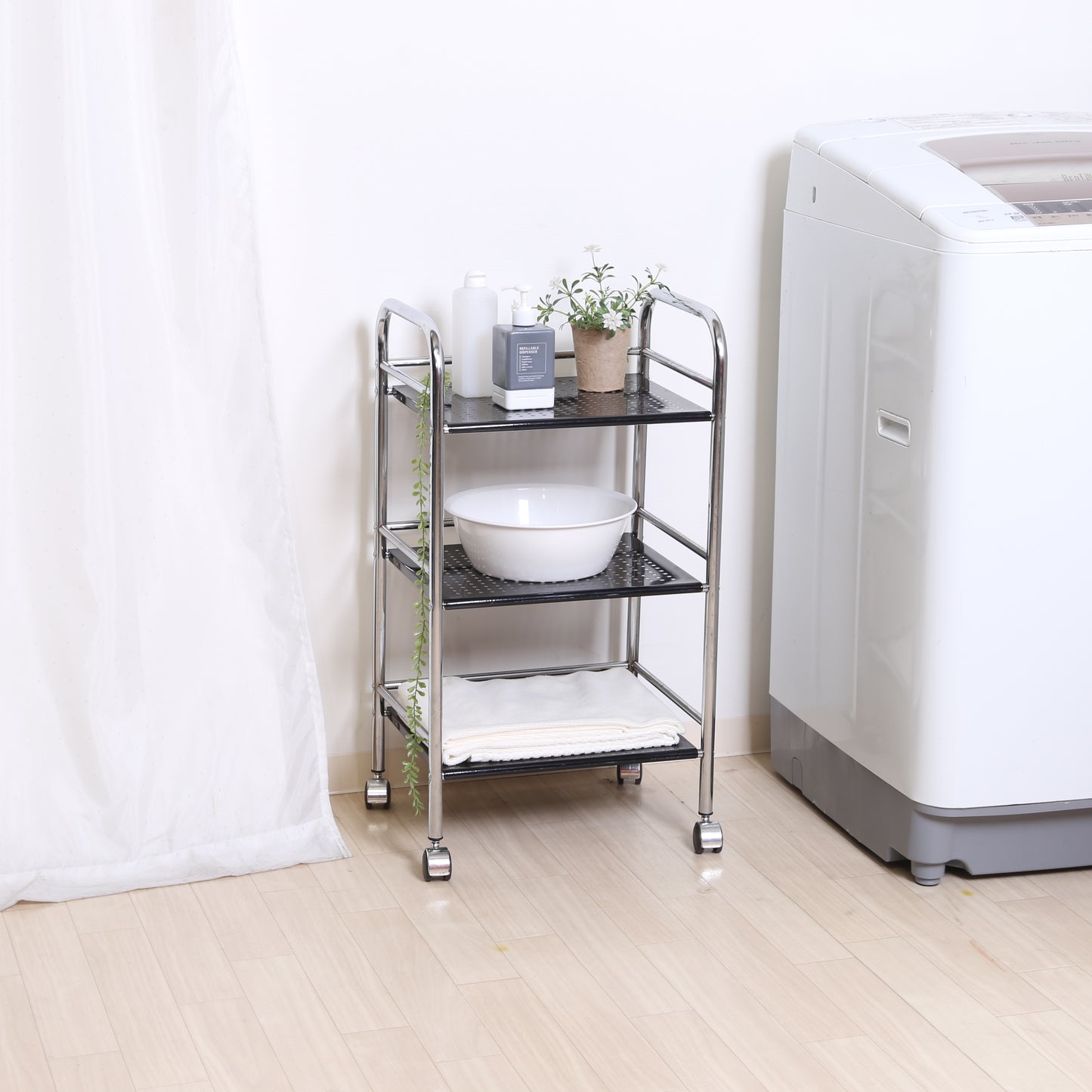 収納板がブラックのスチールワゴンを洗濯機の横に置いている様子