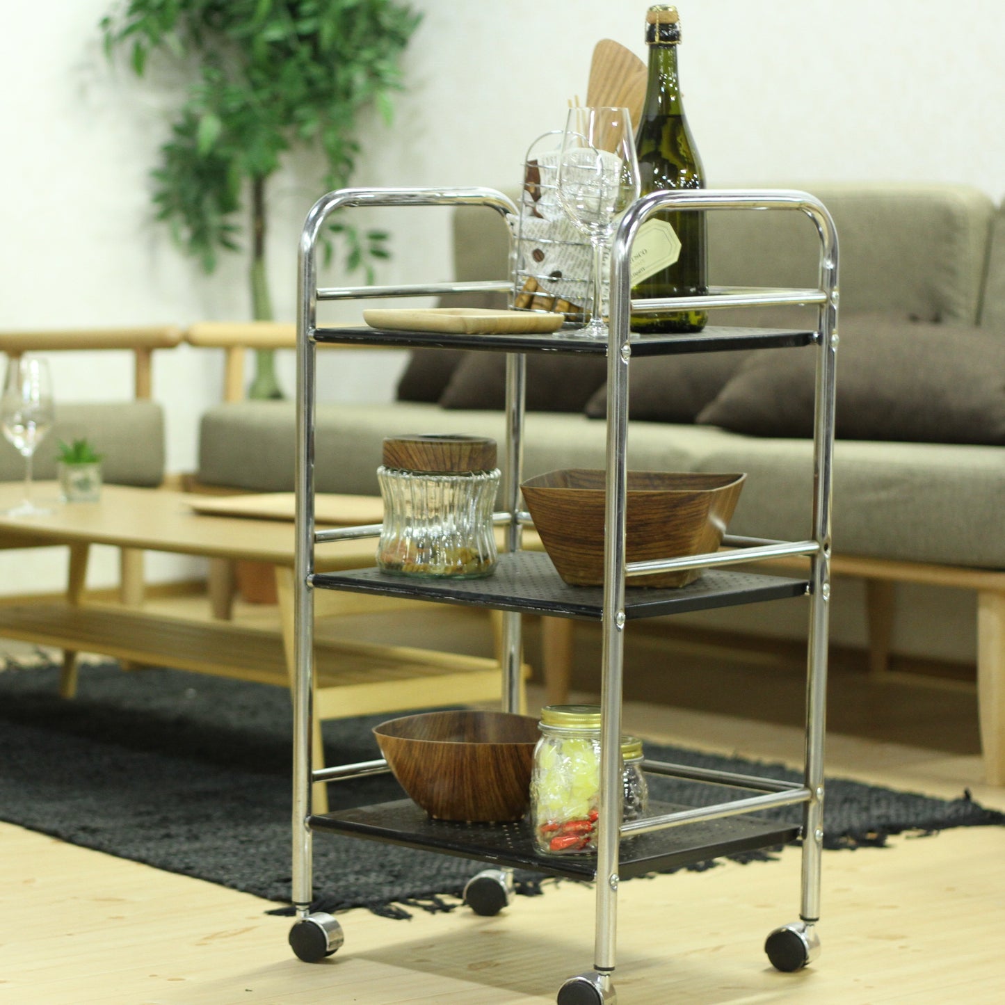 収納板がブラックのスチールワゴンにワインやグラス、食器、食料品が置かれてある様子