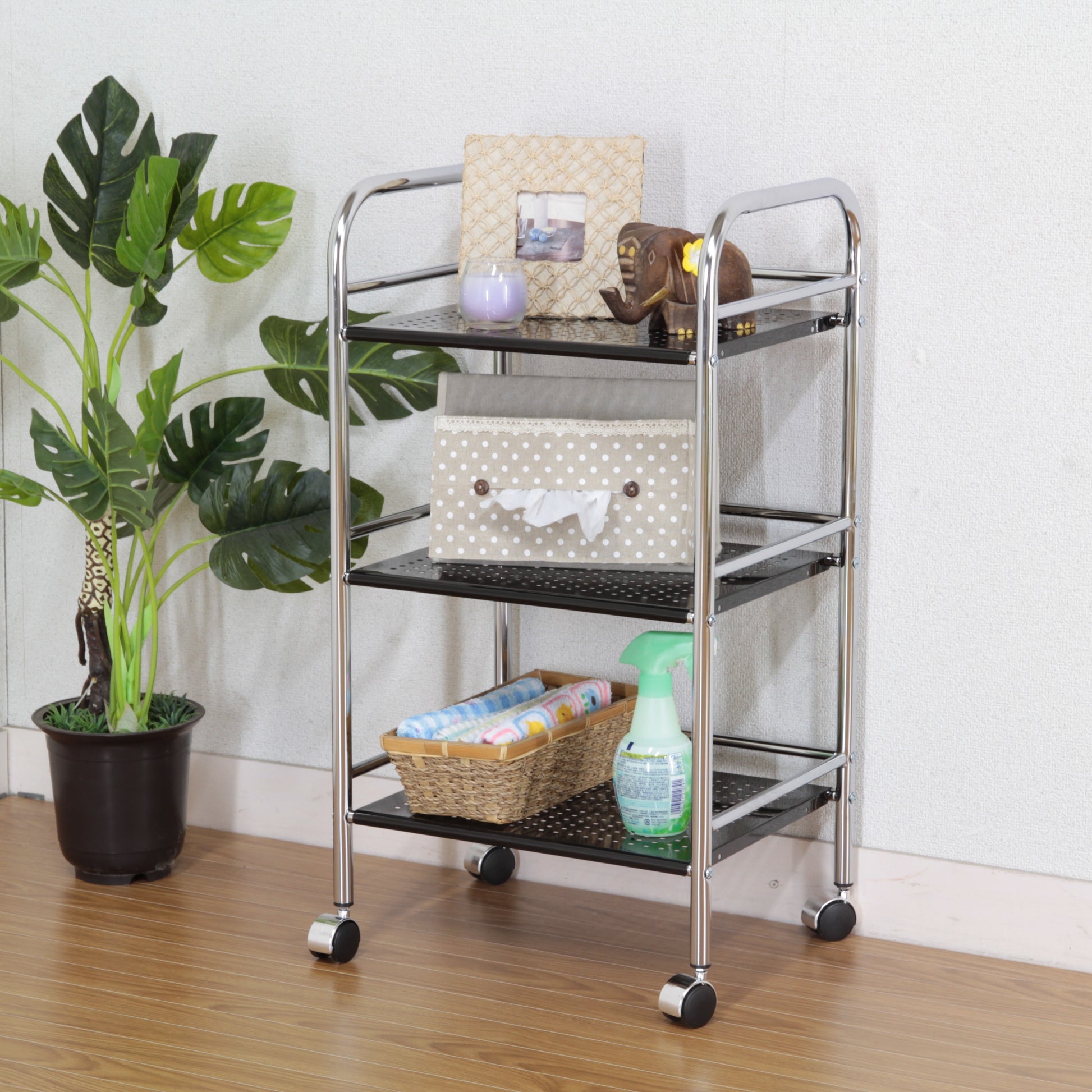 収納板がブラックのスチールワゴンにティッシュケースや写真立て、キャンドルなどを置いている様子