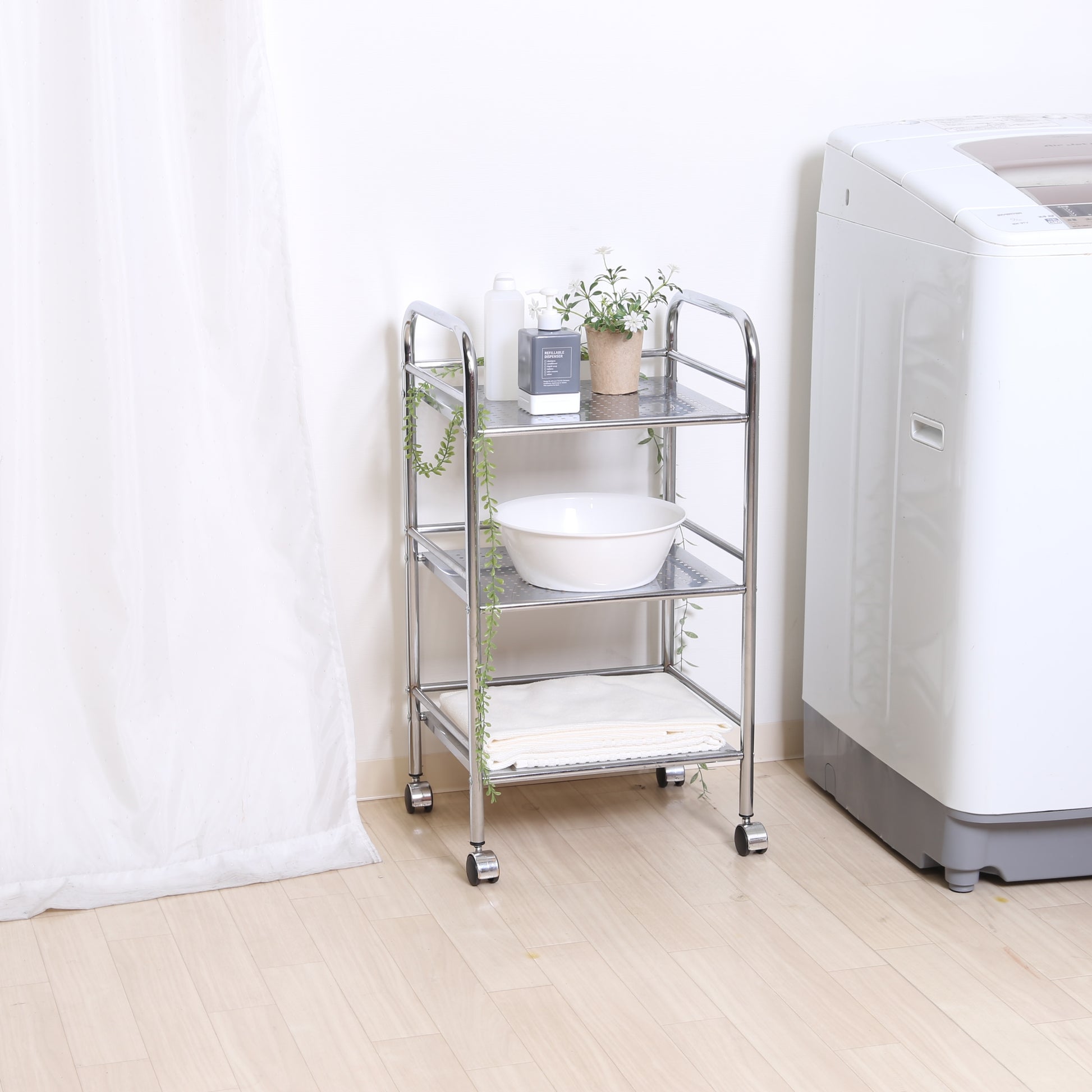 収納板がクリアのスチールワゴンを洗濯機の横に置いている様子