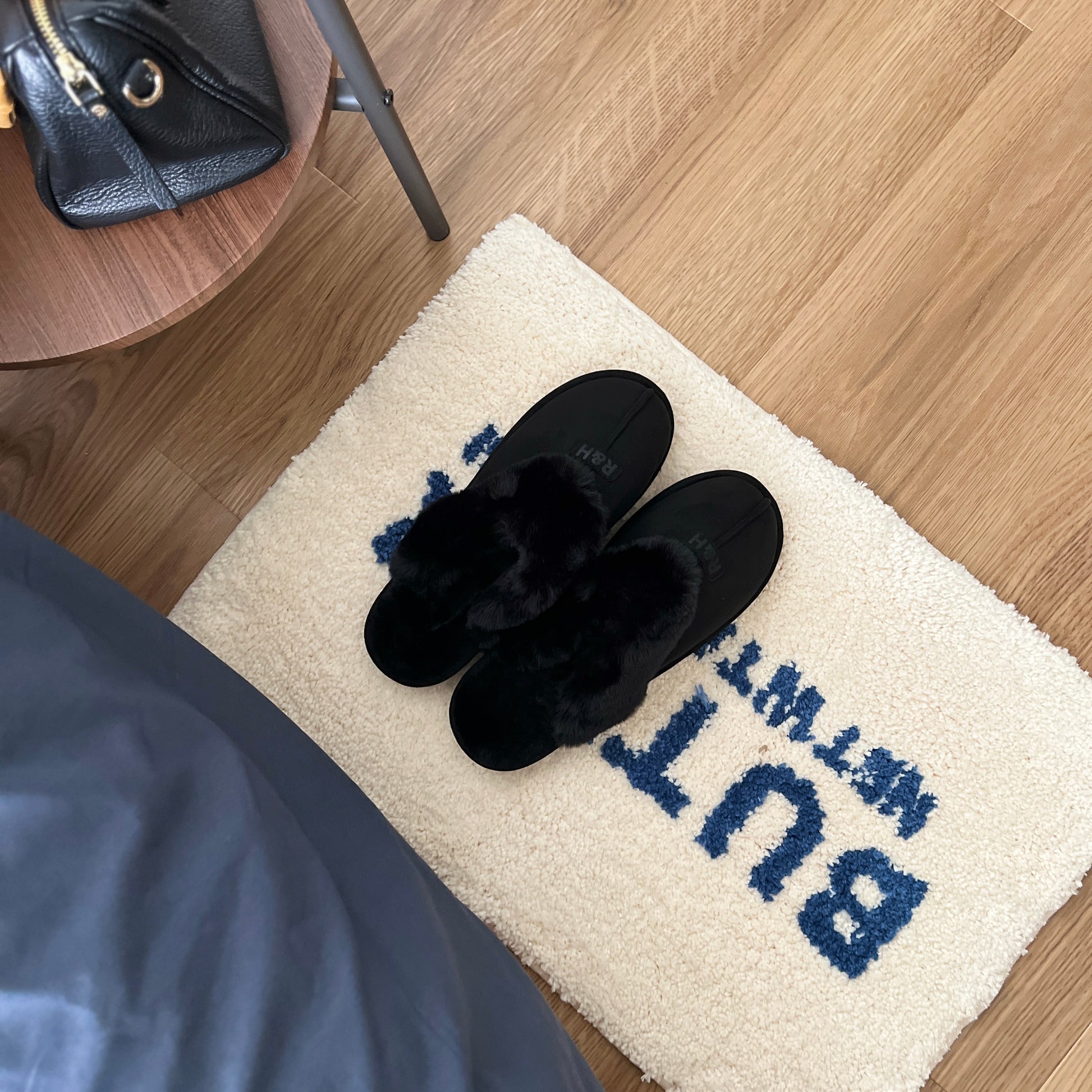 ブラックのムートン調のファースリッパをミニラグの上に置いている様子