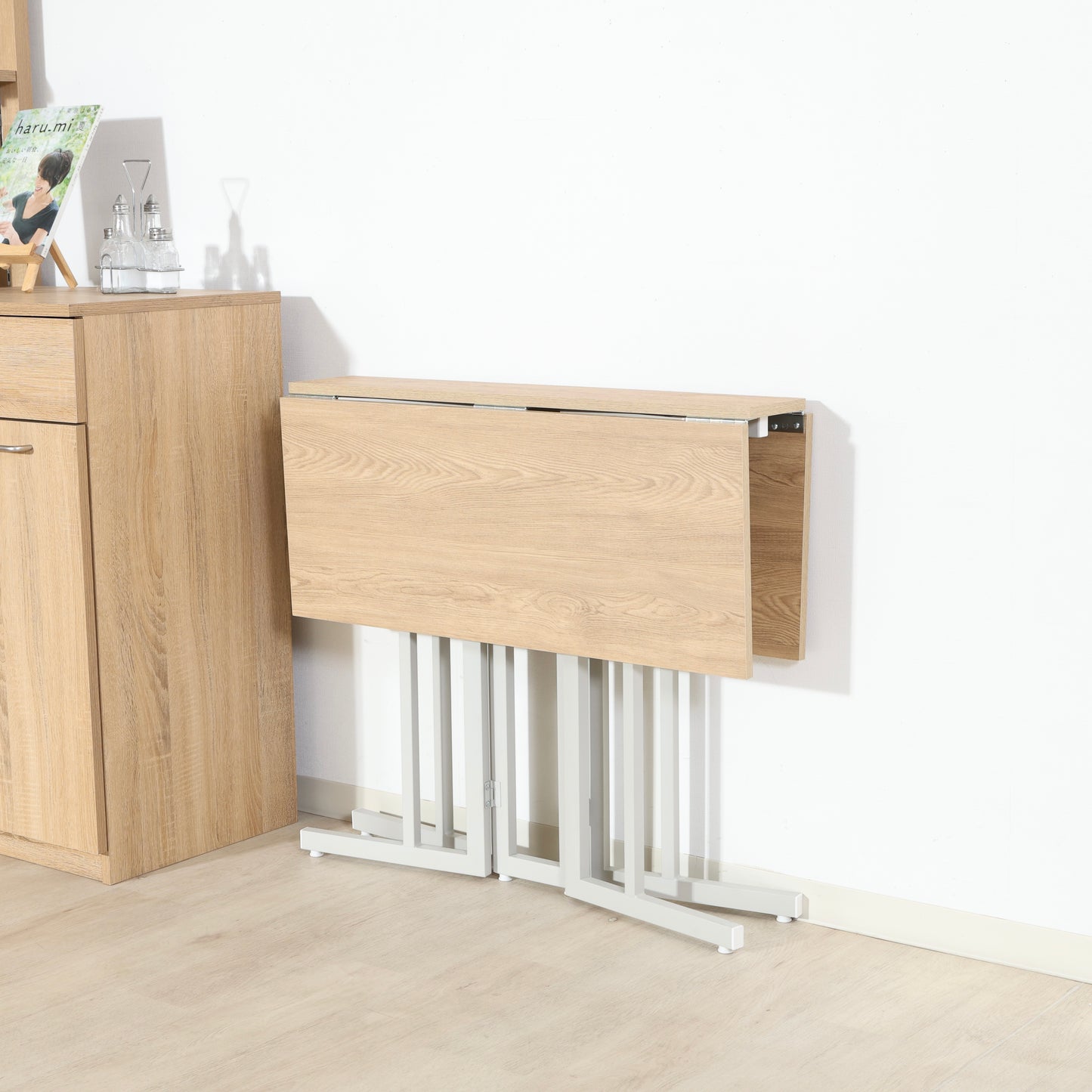 ウッド天板とスチール脚の異素材組み合わせの折りたたみ式のダイニングテーブルが折り畳まれている様子