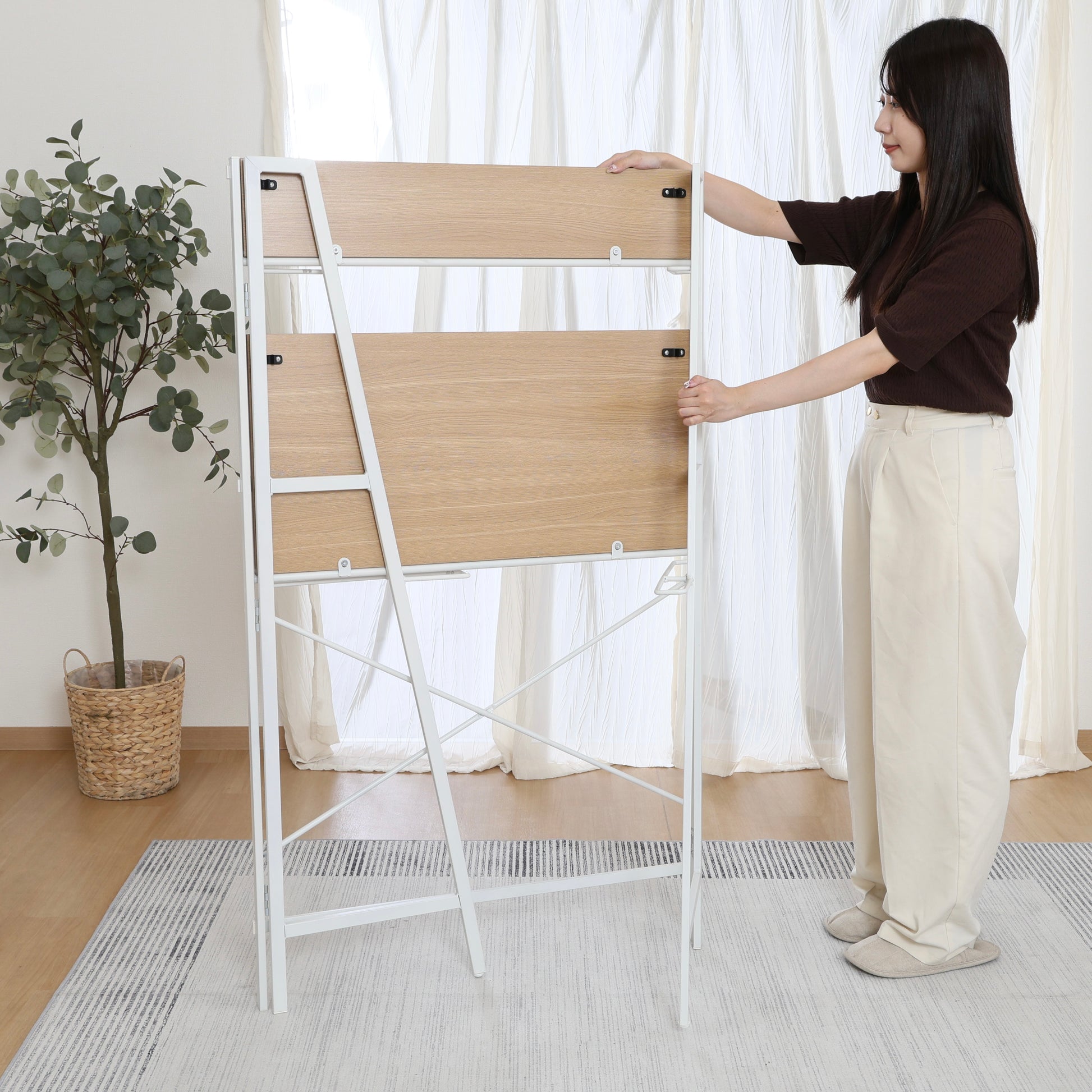 収納棚が付いた折りたたみ式のデスクを折りたたんでいる様子