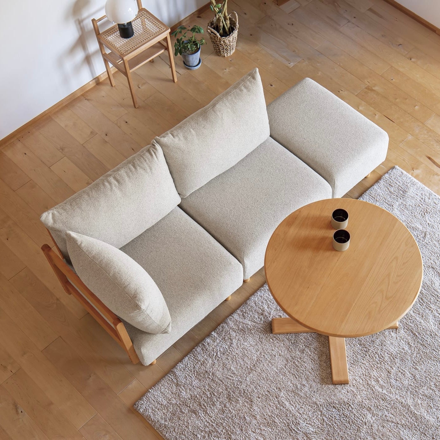 木製フレームのベージュのソファがリビングに置かれている様子