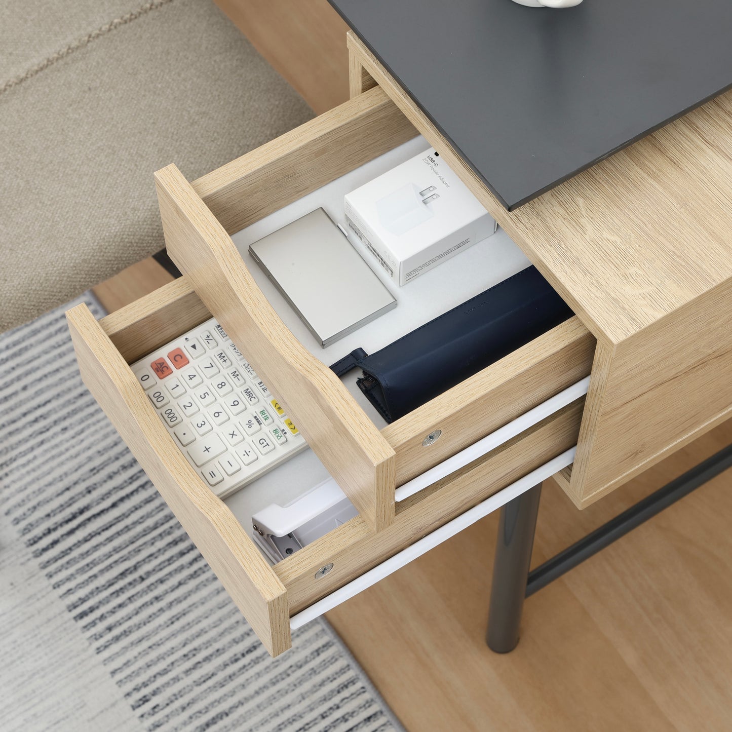 引き出しが付いたバイカラーデザインが特徴のデスクの引き出しに文房具が収納されている様子
