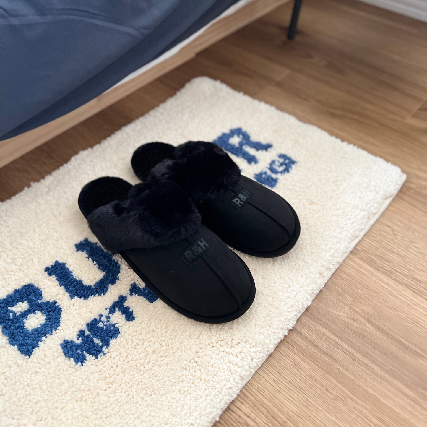 ブラックのムートン調のファースリッパをミニラグの上に置いている様子