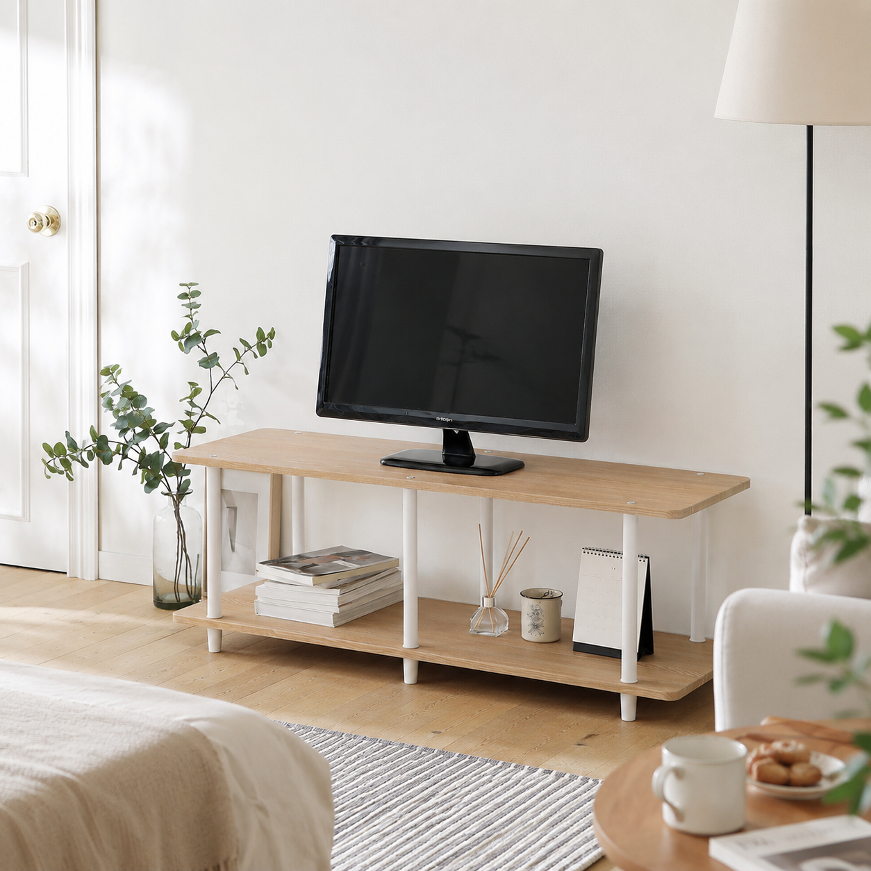 Roomnhome｜組立式リビングボードの白脚付きライト木目調テレビ台に黒いモニターが載っています