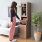 リビングに置かれたブラウンのスリム設計のダストボックス一体型のラックのゴミ箱にゴミを捨てている様子