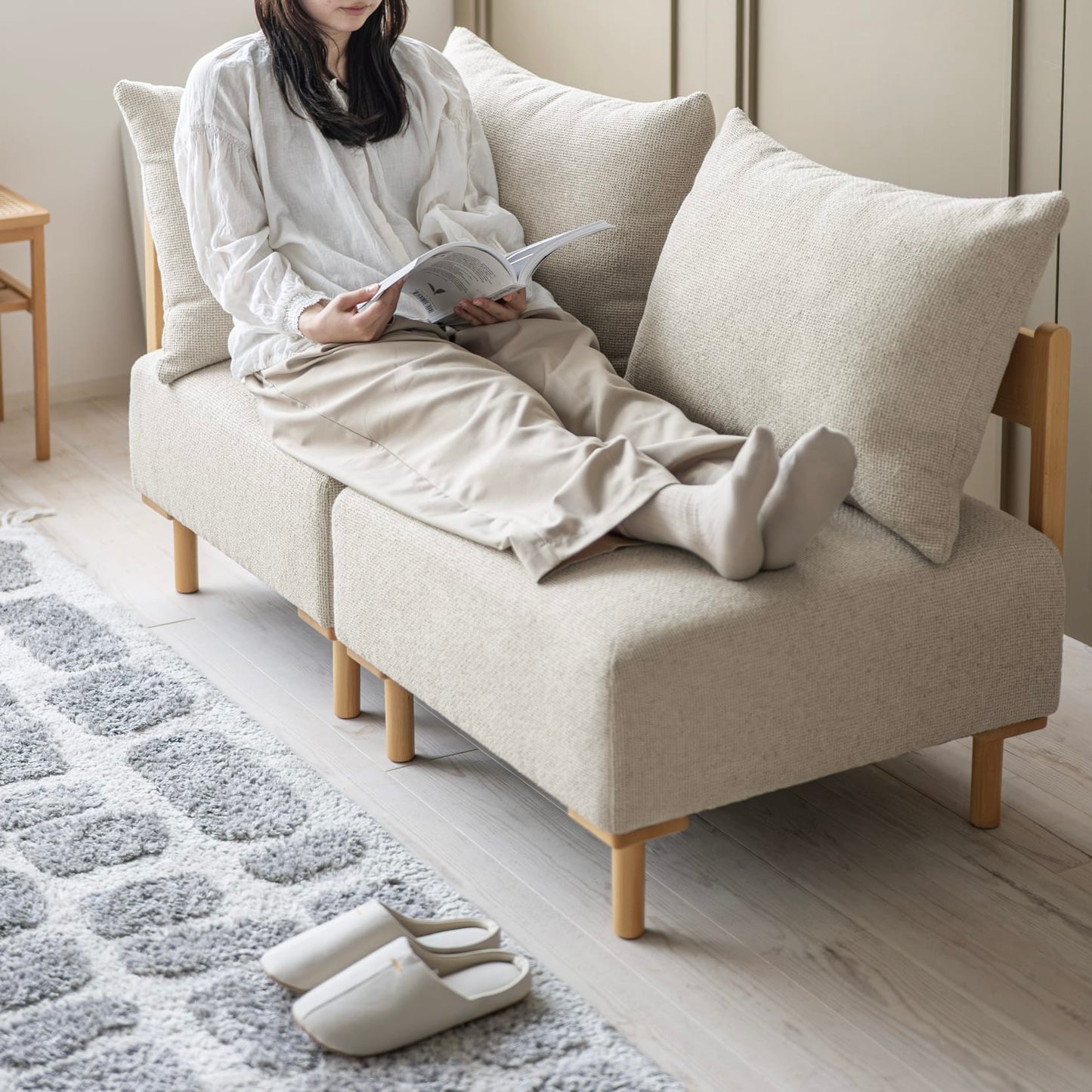 木製フレームのベージュのソファに人が座っている様子