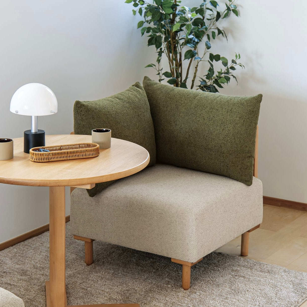 木製フレームのモスグリーンのソファが丸テーブルの前に置かれている様子