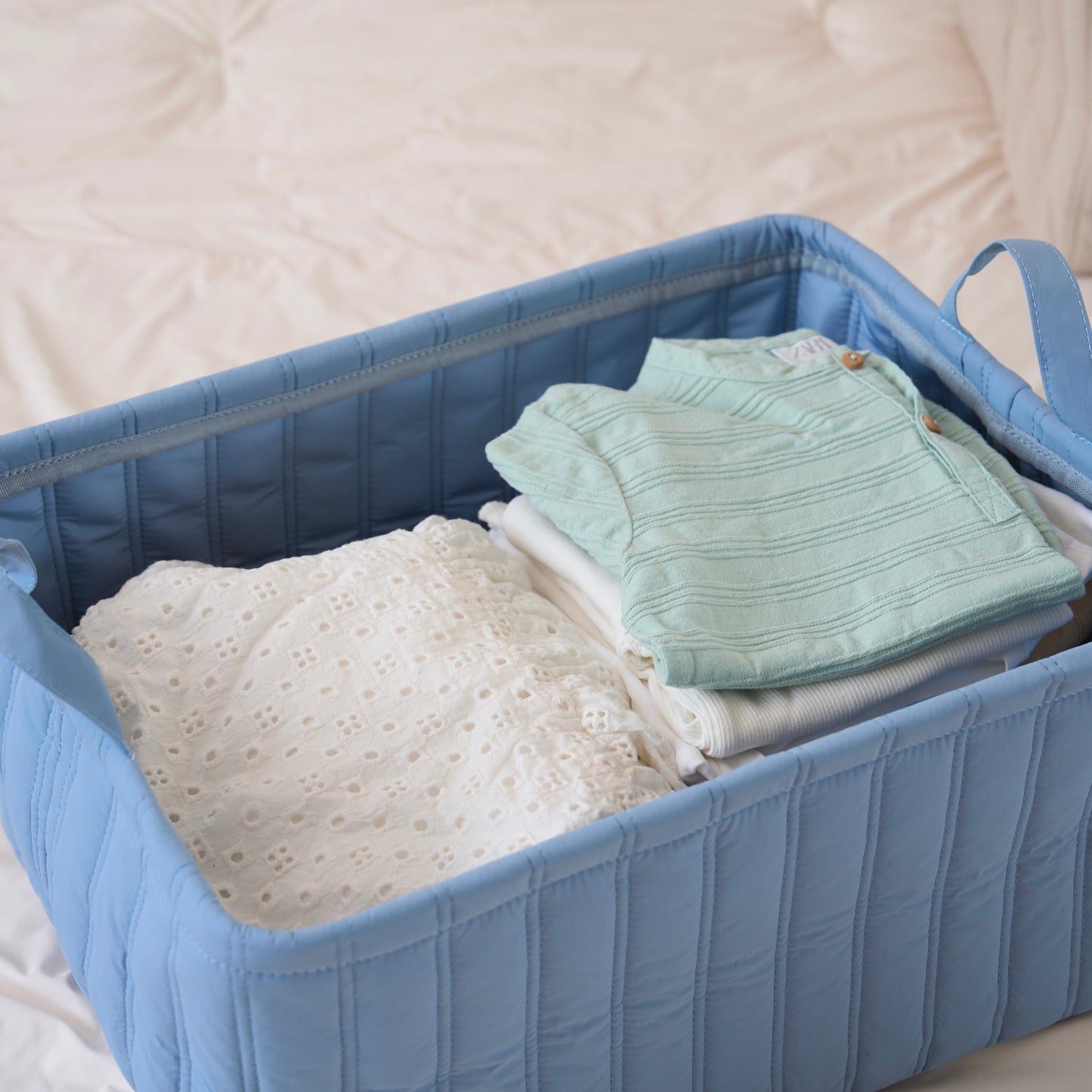 キルティング素材のブルーのバスケットに子供服が収納されている様子