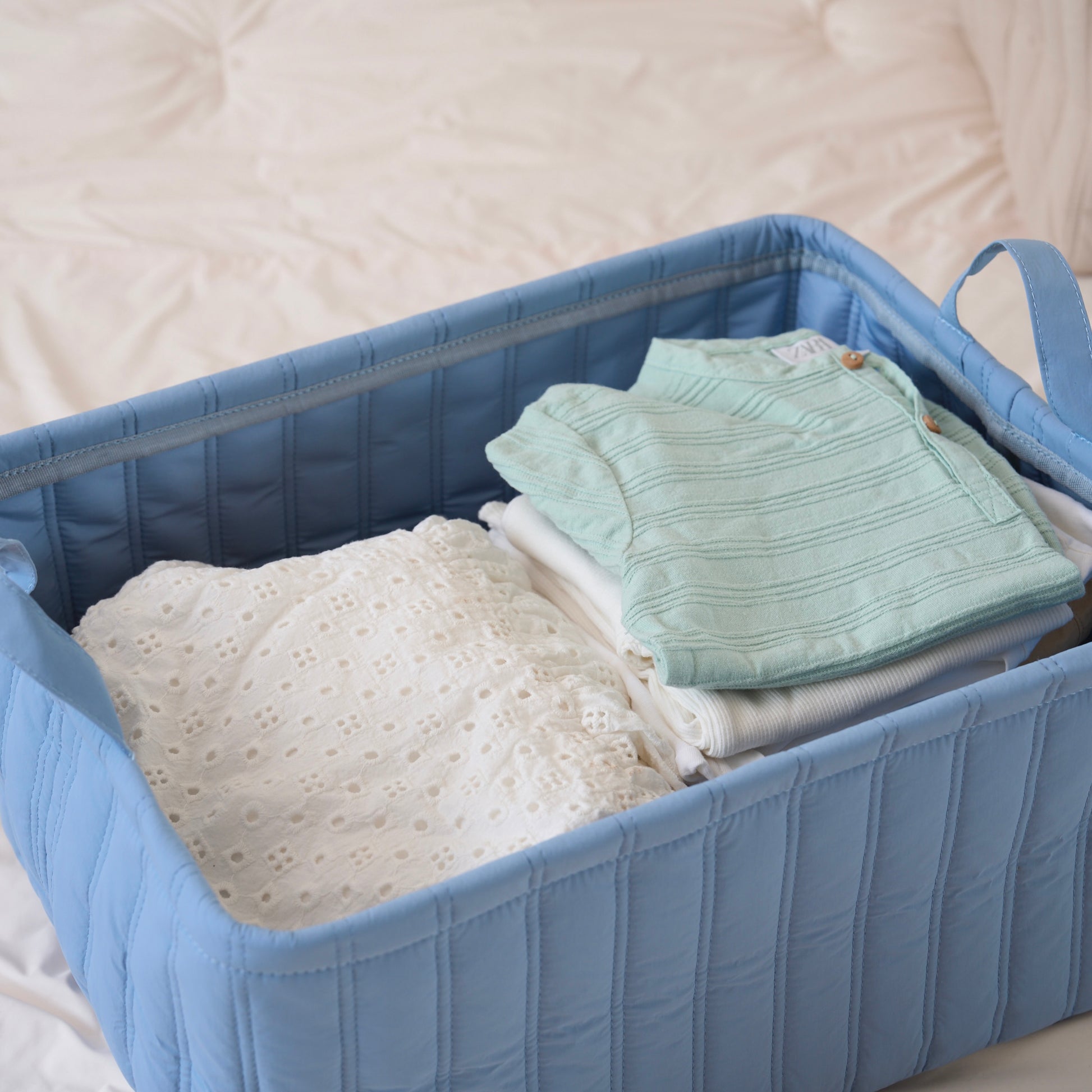 キルティング素材のブルーのバスケットに子供服が収納されている様子