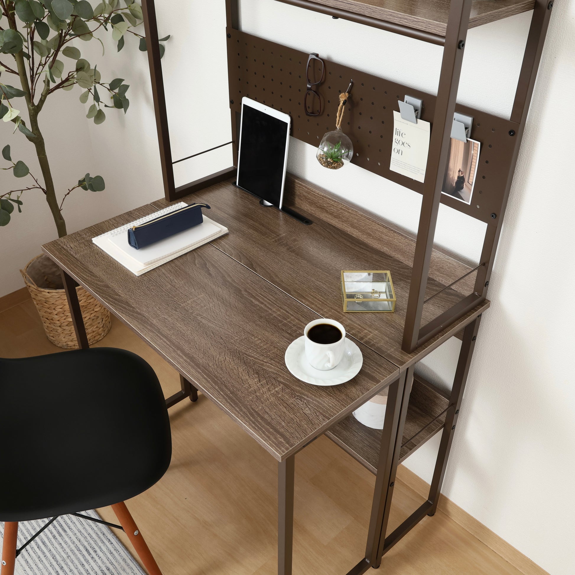 天板が折りたためる収納棚が付いたデスクに文房具とコーヒーが置かれている様子