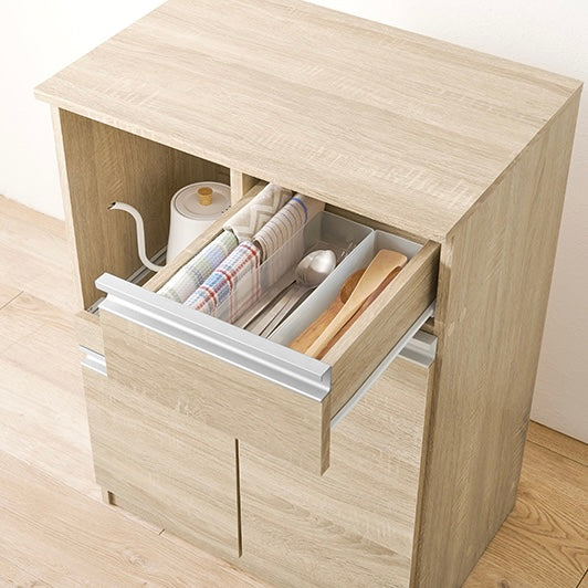 ナチュラルのキッチンボードのスライド引き出しにカトラリーなどの小物が収納されている様子