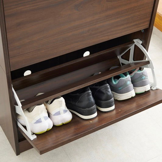 ブラウンのフラップ扉式シューズケースに靴を収納している様子