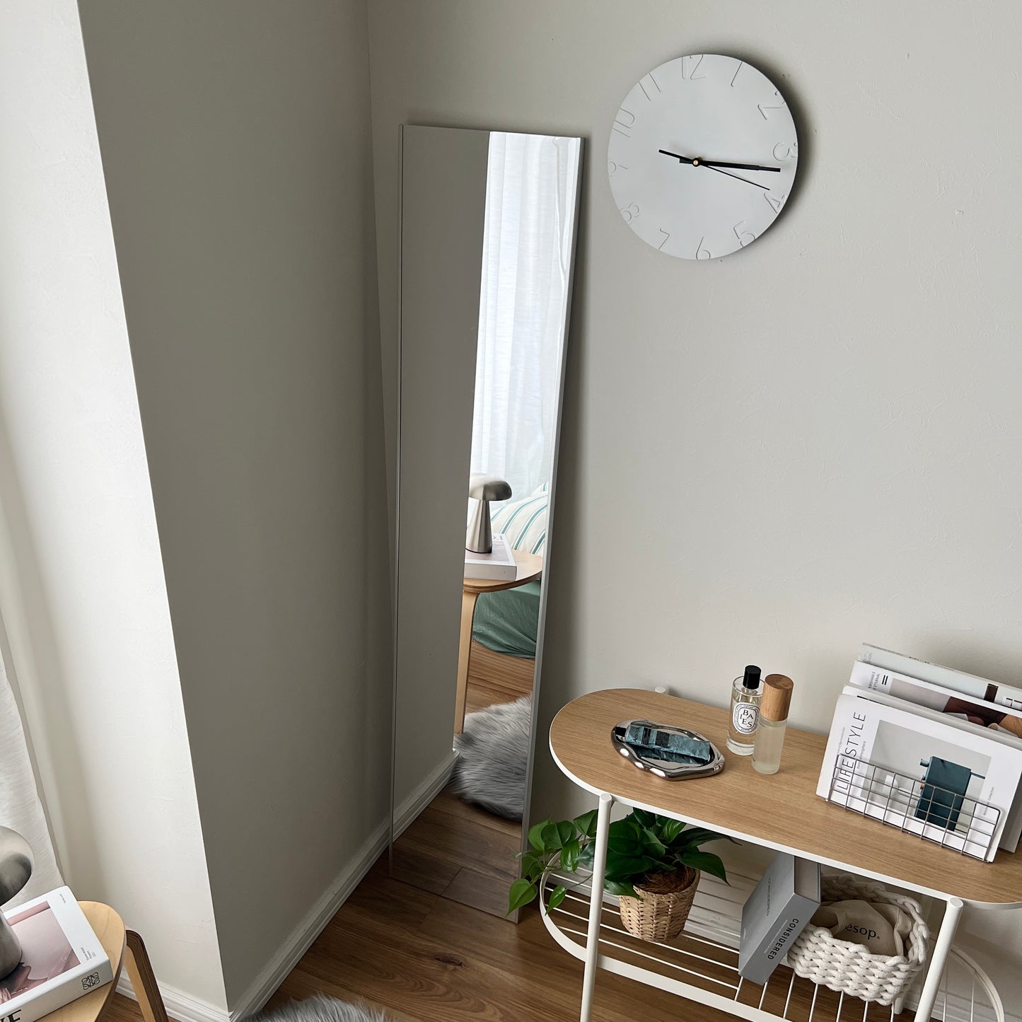 全身鏡の右上の壁に壁掛け時計がかかっている様子