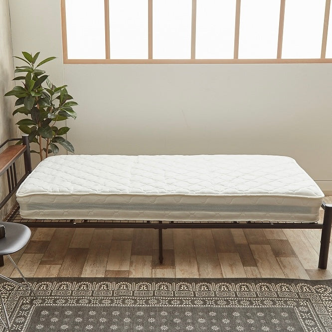 ホワイトのポケットコイルマットレスをベッドの上に置いている様子