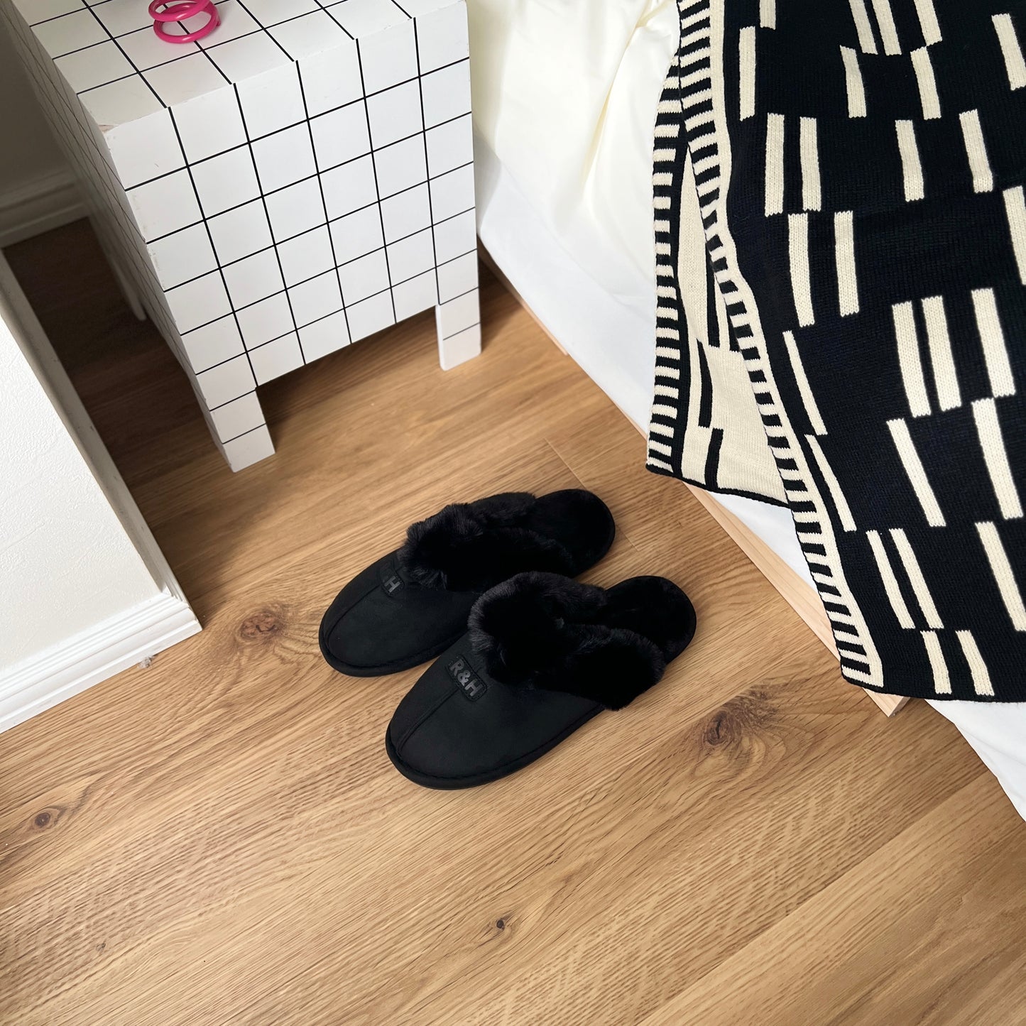 ブラックのムートン調のファースリッパをベッド横に置いている様子