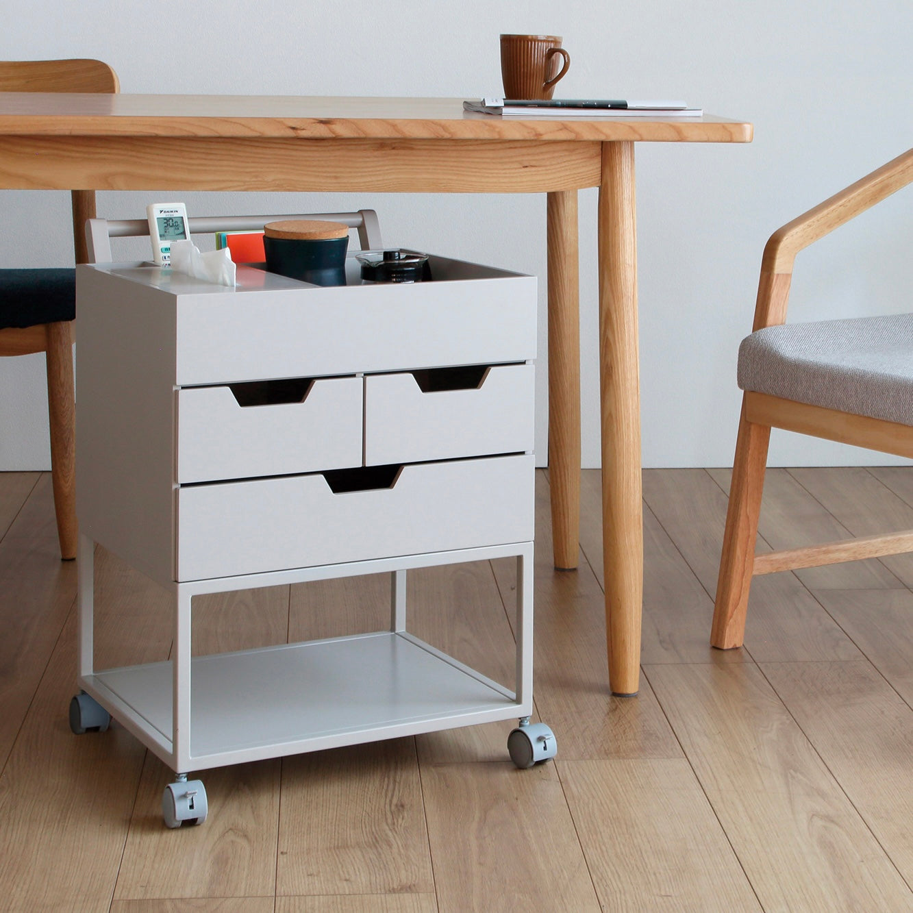 引き出しがたくさんついたグレーのワゴンがテーブルの下に置かれている様子