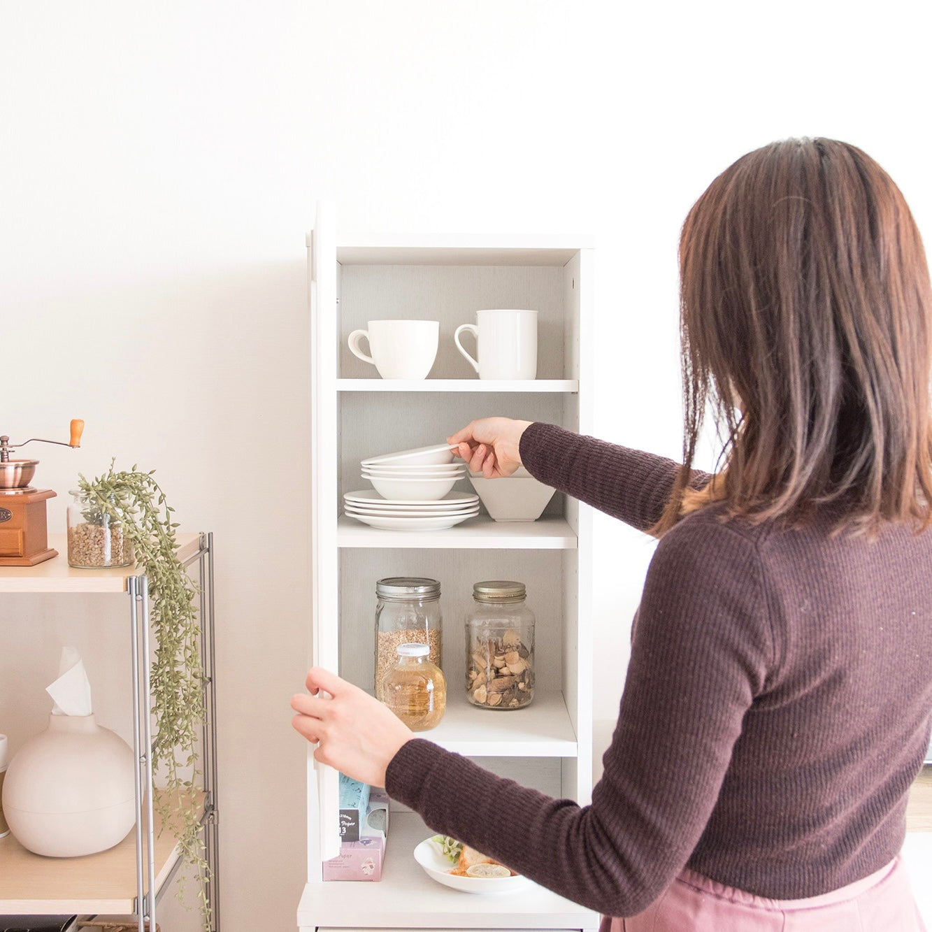 キッチンに置かれたホワイトのスリム設計のダストボックス一体型のラックに食器や食品が収納されている様子