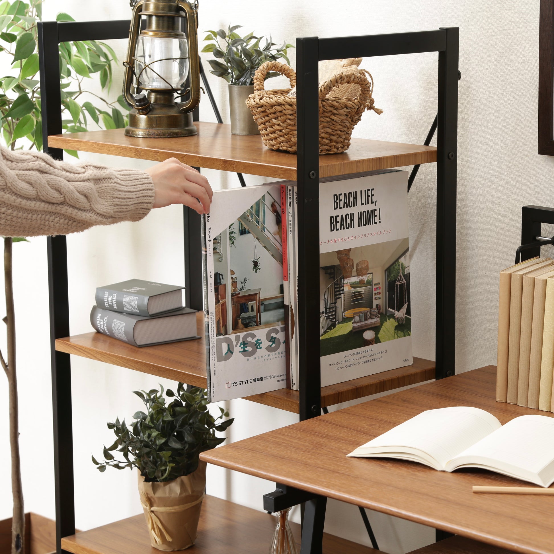 ウッド素材の天板と黒スチールのフレームの4段シェルフに本を収納している様子