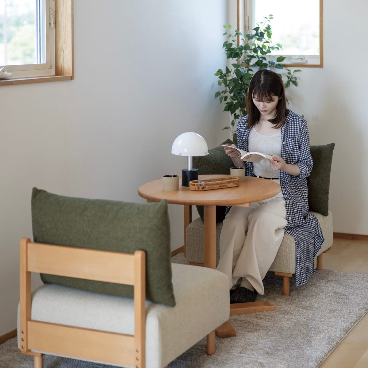 木製フレームのモスグリーンのソファに人が座っている様子