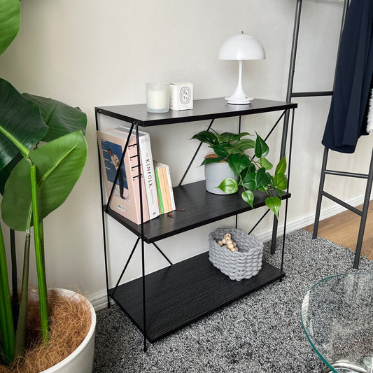 ブラックの2段シンプルワイヤーラックにランプやキャンドル、植物、本などを置いている様子