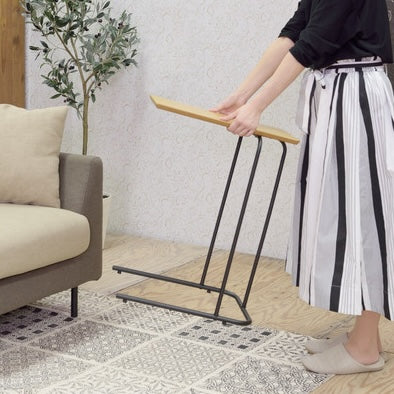 木目調の天板のコンパクトなサイドテーブルを持ち上げている様子