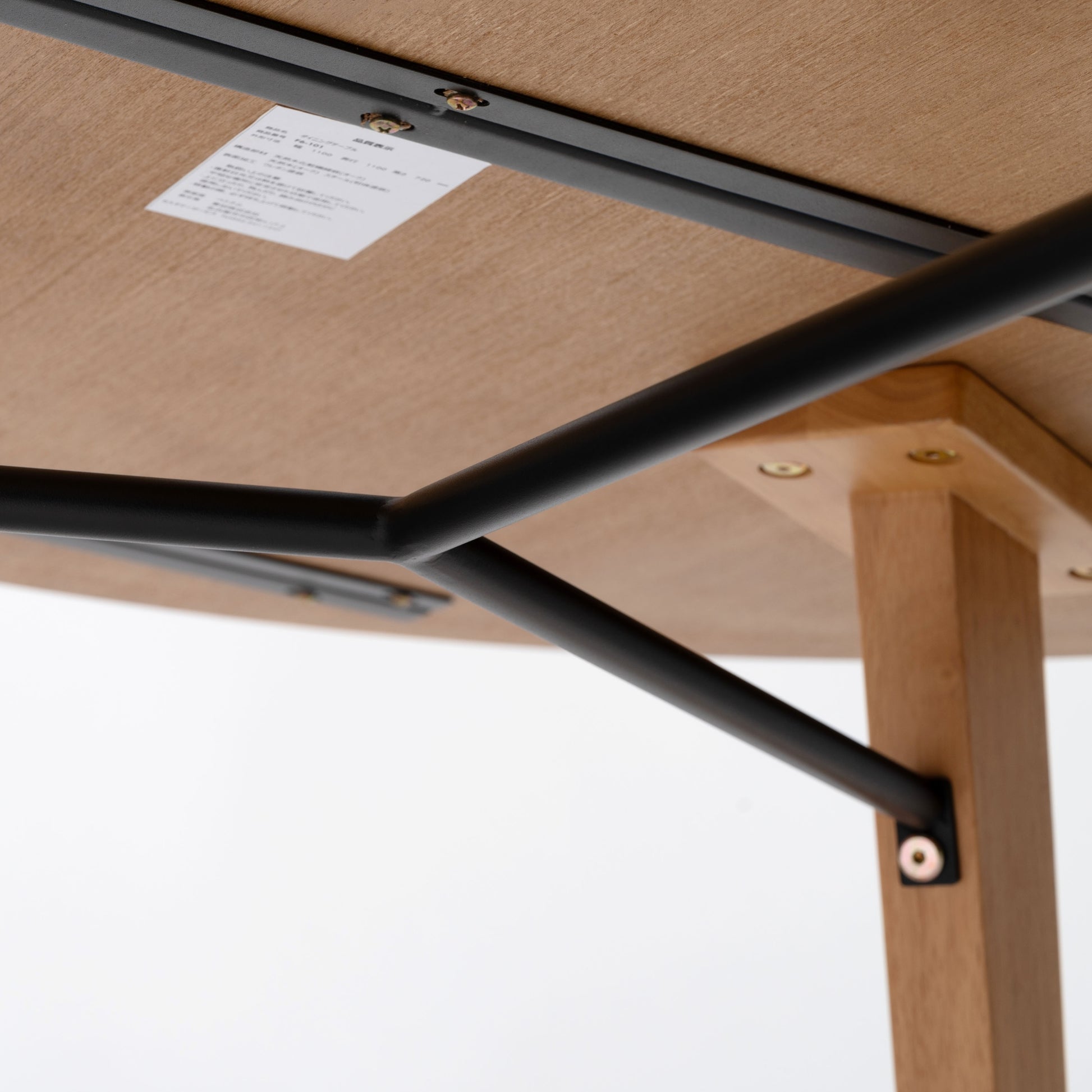 天然木の素材を使用した直径110cmの円形ダイニングテーブルの天板裏の黒いスチール製のバーのアップの写真