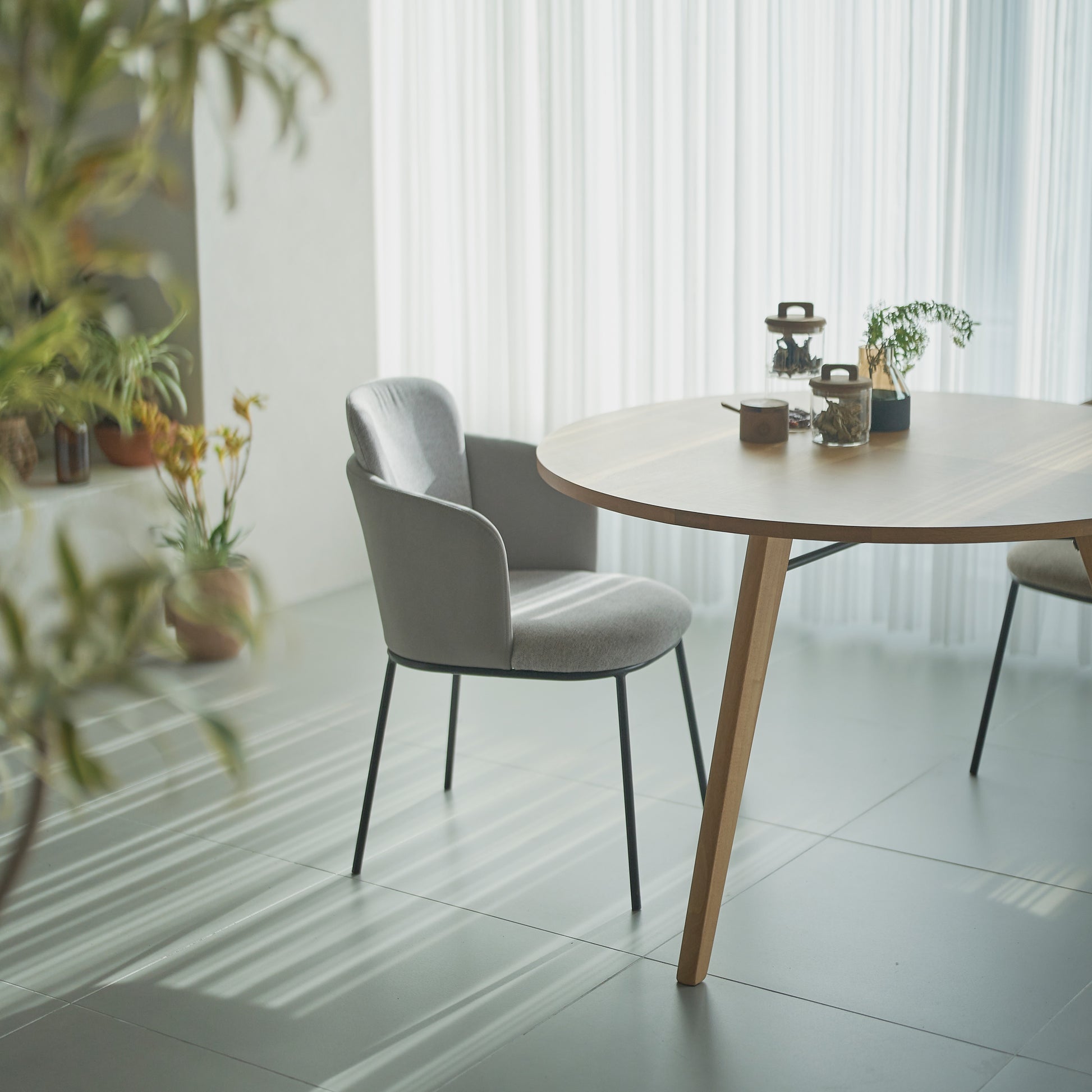 部屋のリビングで天然木の素材を使用した直径110cmの円形ダイニングテーブルにグレーの張り地のチェアを合わせたインテリアコーディネート