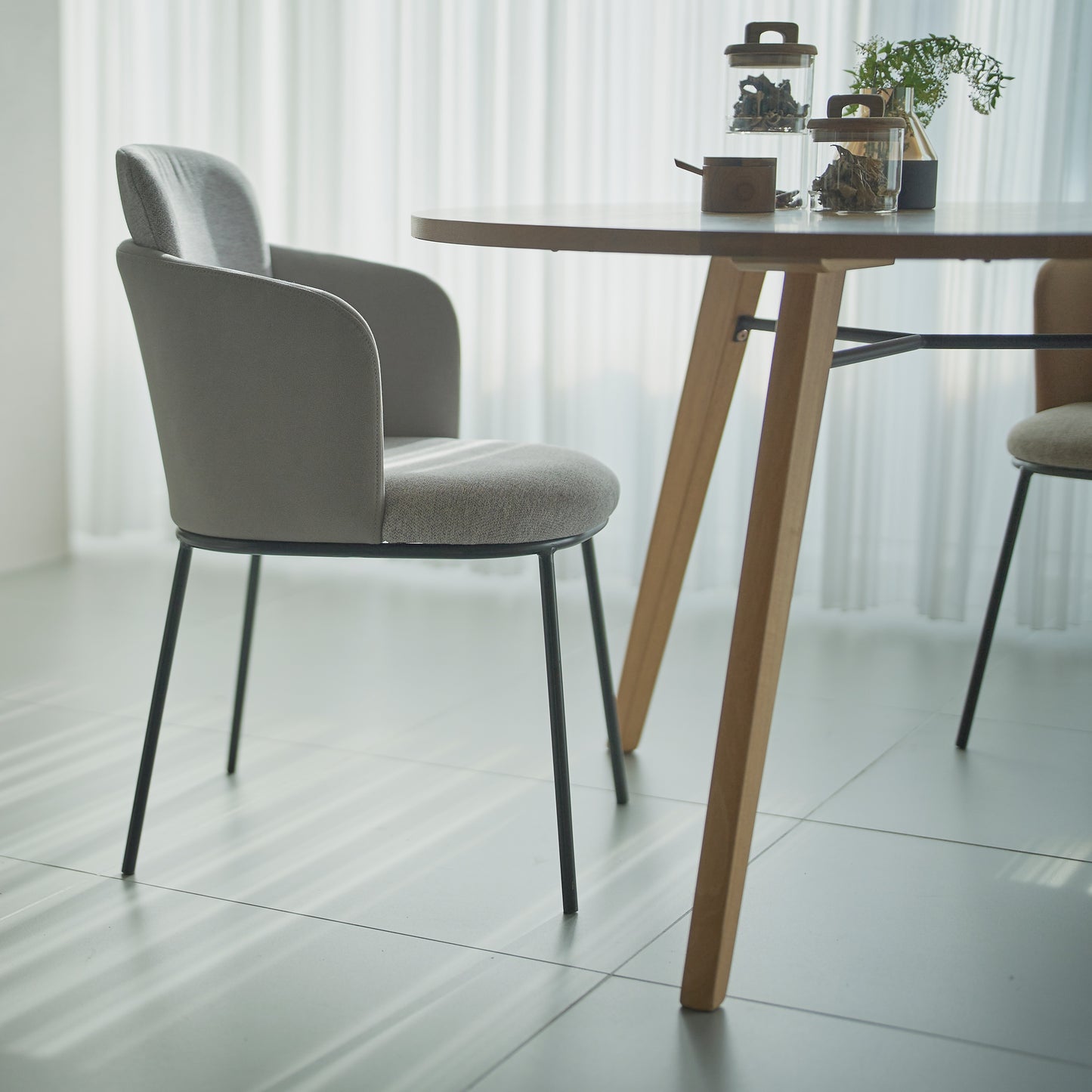 部屋のリビングで天然木の素材を使用した直径110cmの円形ダイニングテーブルにグレーの張り地のチェアを合わせたインテリアコーディネート
