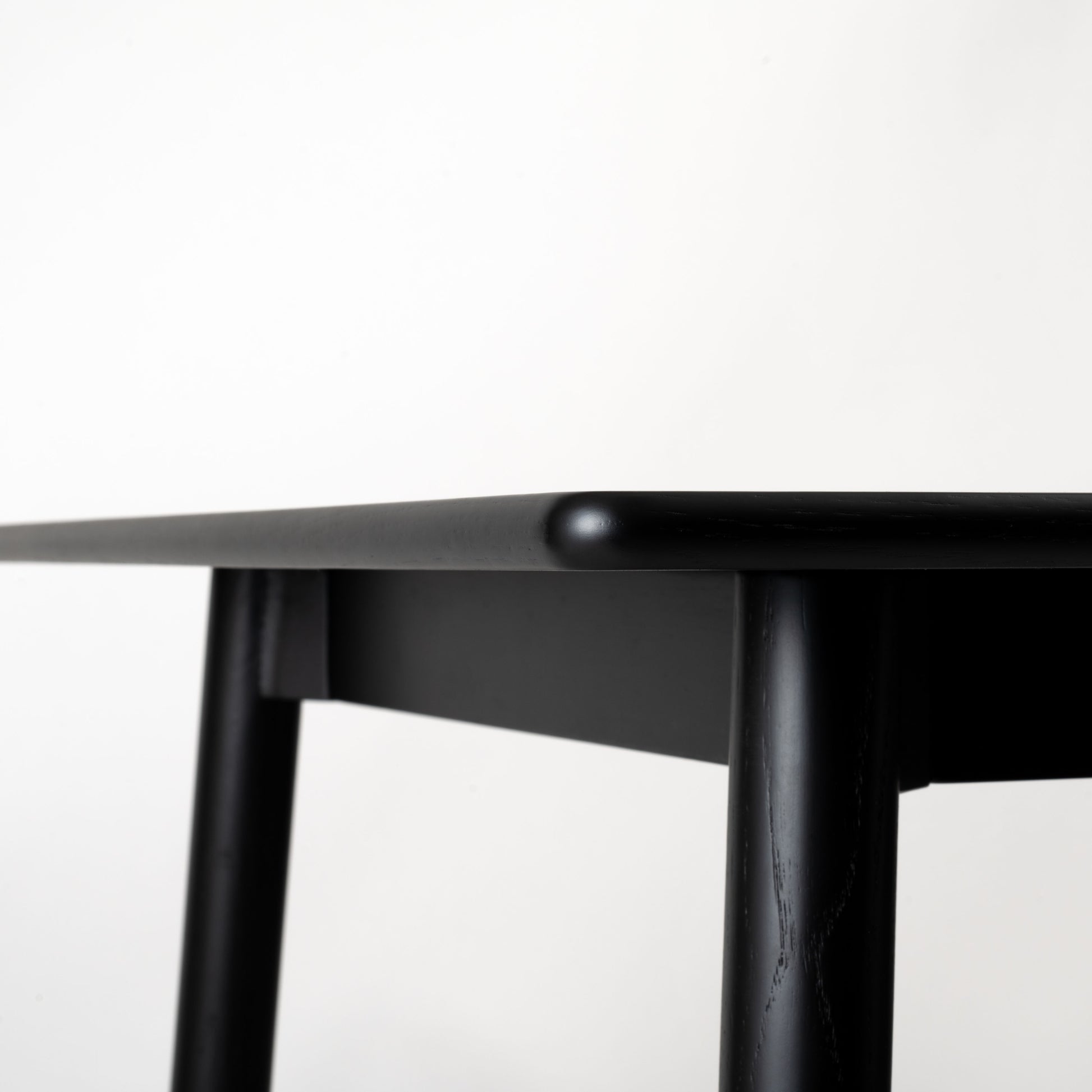 天然木オーク材を天板と脚部に使用しウレタン塗装でブラックに塗られたワントーンデザインのダイニングテーブルの天板の角のアップの写真