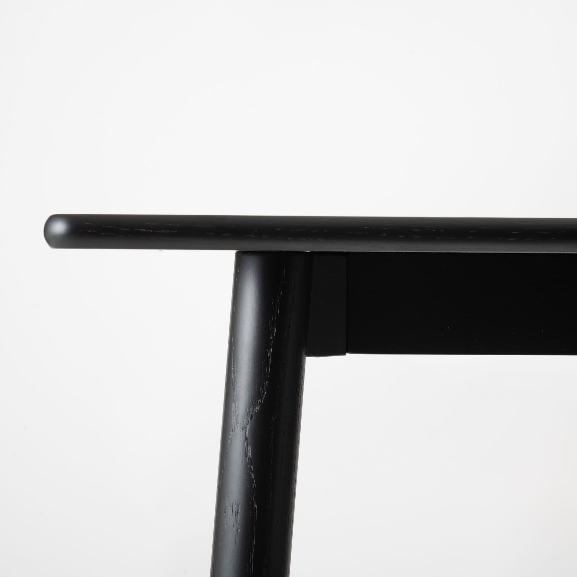 天然木オーク材を天板と脚部に使用しウレタン塗装でブラックに塗られたワントーンデザインのダイニングテーブルの天板を真横から見た写真